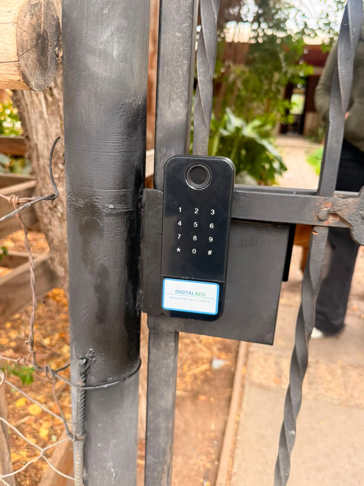 Cerradura digital con huella instalada en reja de fierro forjado con acceso a jardin